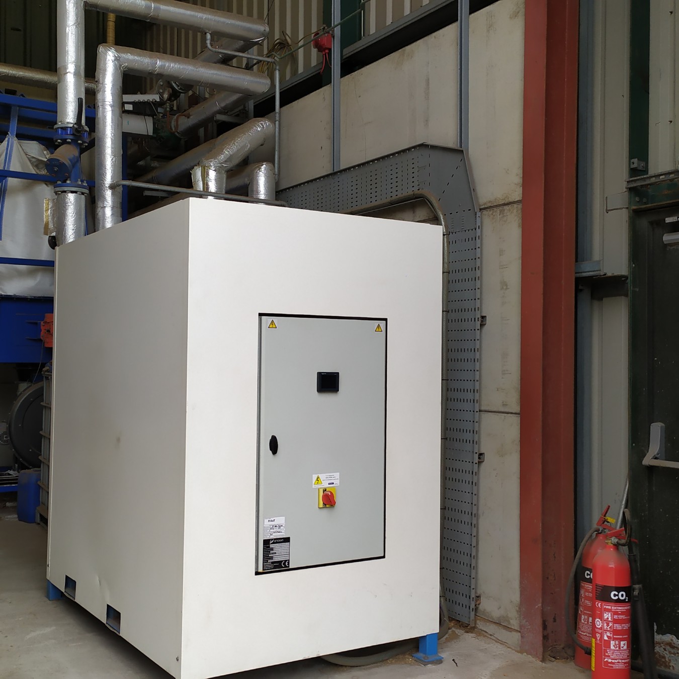 Front view of a 40kWe Organic Rankine Cycle (ORC) unit on its skid, connected to a Ranheat biomass boiler, showcasing electricity generation from hot water heating systems.